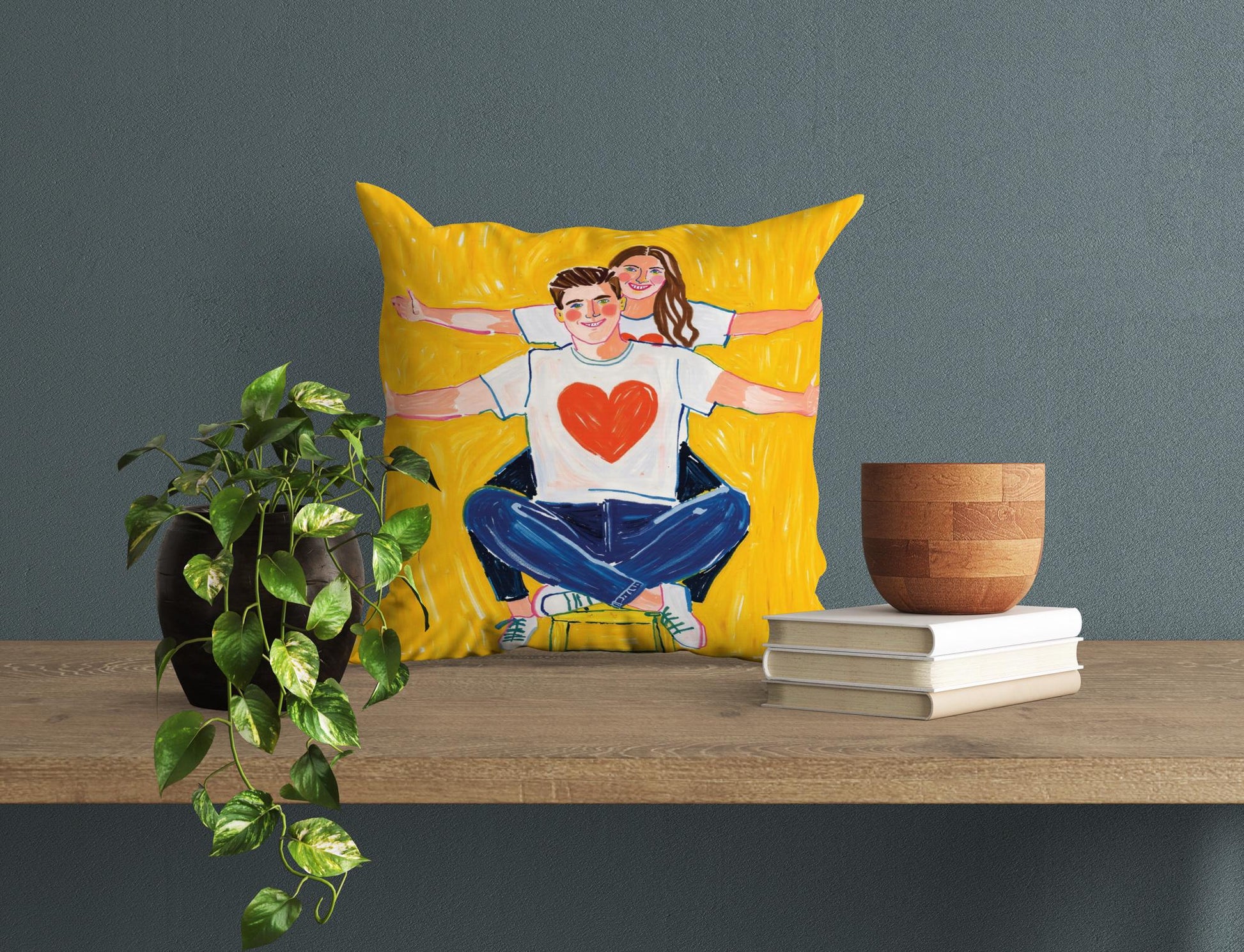 Yellow square pillow with a cartoonish couple. Bright colors, on a shelf, cheerful wedding gift.