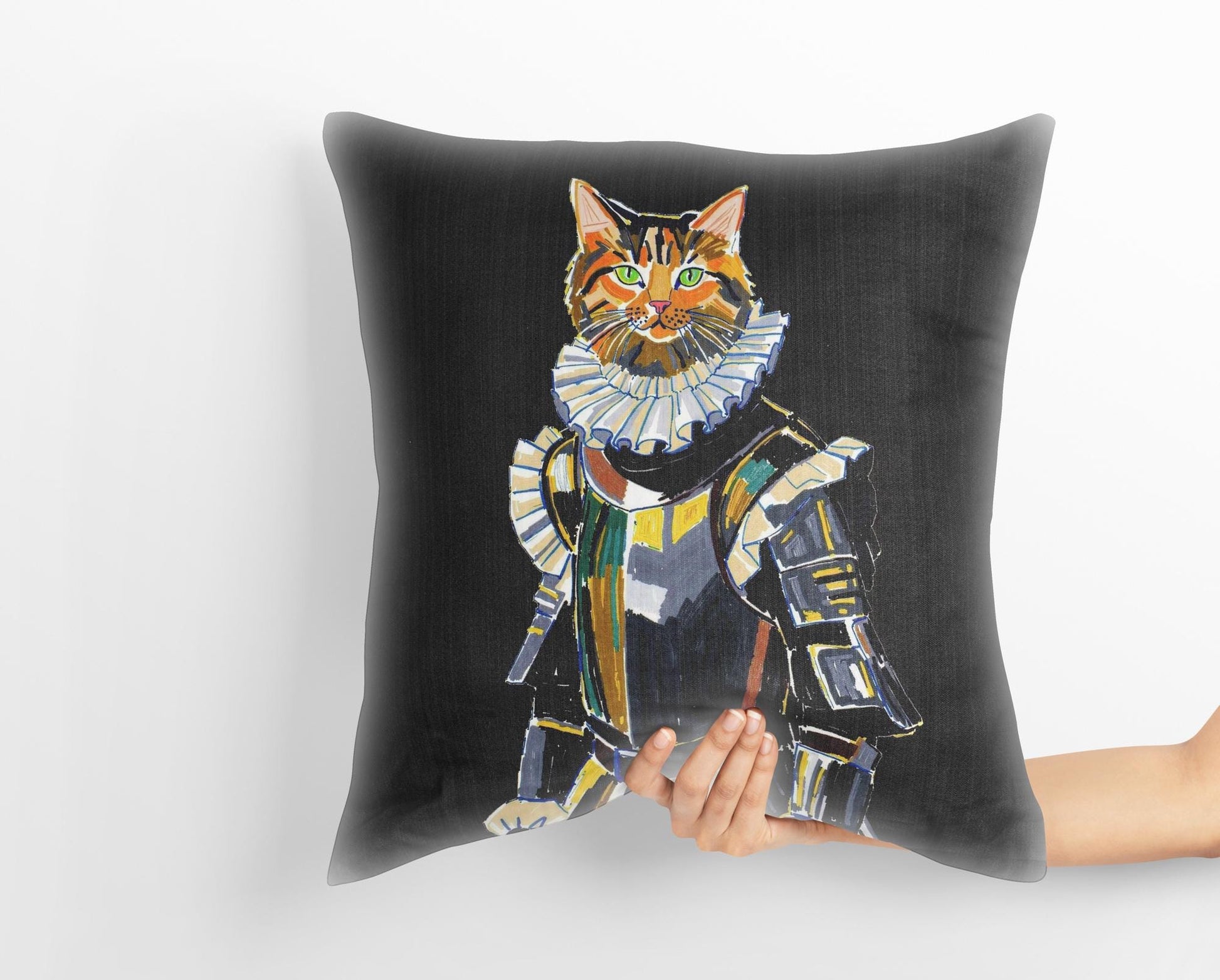 A hand holds a custom medieval pet portrait pillow featuring a tabby cat dressed as a knight in shining armor. The whimsical art captures the heroic spirit of the pet.