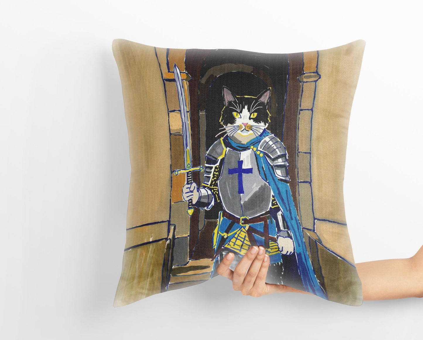 A hand holds a custom medieval pet portrait pillow featuring a black and white cat dressed as a knight in shining armor, standing in a stone archway. The whimsical art captures the heroic spirit of the pet.