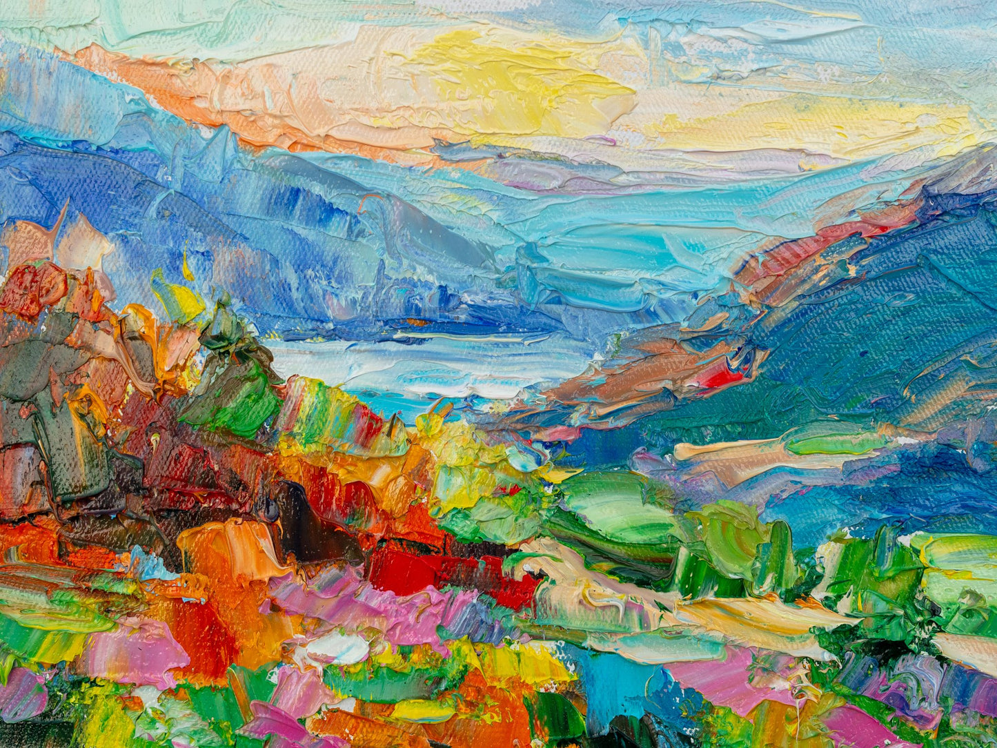 Vibrant oil painting of a mountain valley with bold brushstrokes in blue, green, and yellow; unframed canvas on neutral surface