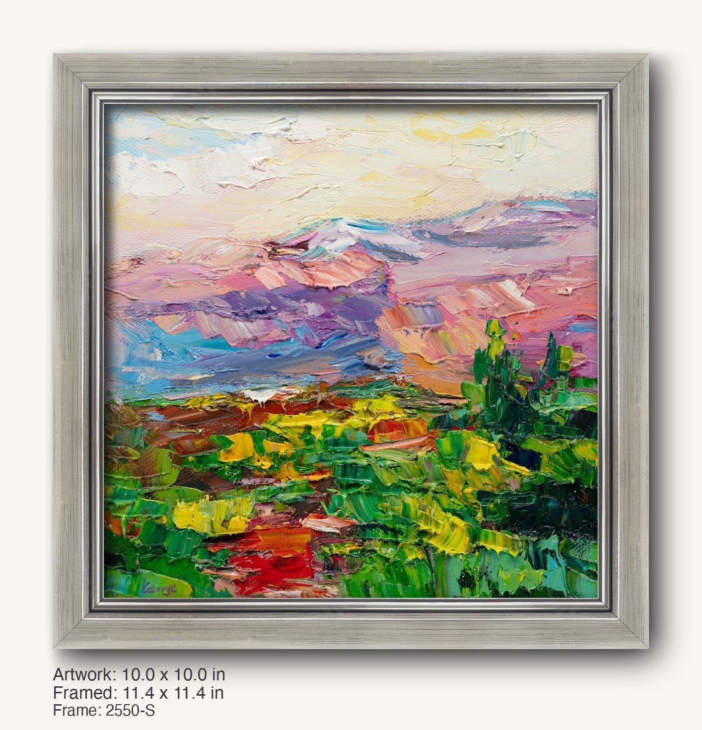 Vibrant desert sunset oil painting in a modern slim silver frame, featuring textured brushstrokes of pink, blue, and green hues with distant mountains and foreground foliage.
