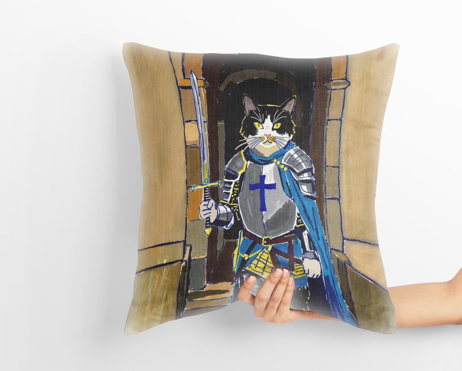 A hand holds a custom medieval pet portrait pillow featuring a black and white cat dressed as a knight in shining armor, standing in a stone archway. The whimsical art captures the heroic spirit of the pet.