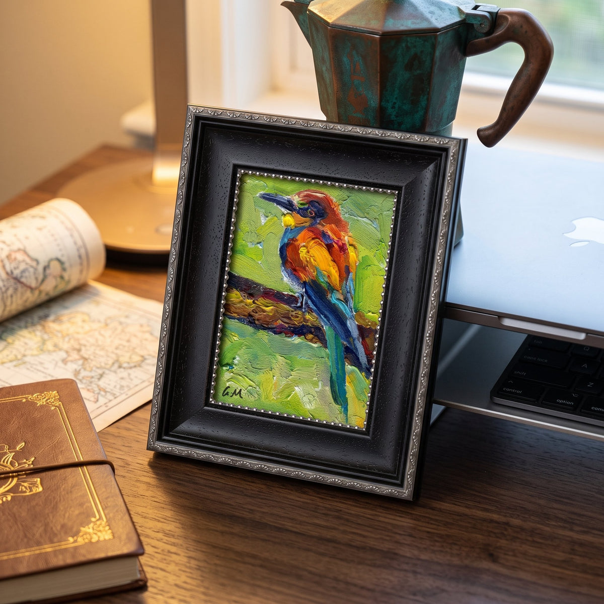 A vividly painted bird perched on a branch, rendered in expressive oil strokes of orange, blue, and green, sits framed on a wooden desk beside a vintage map and leather journal.