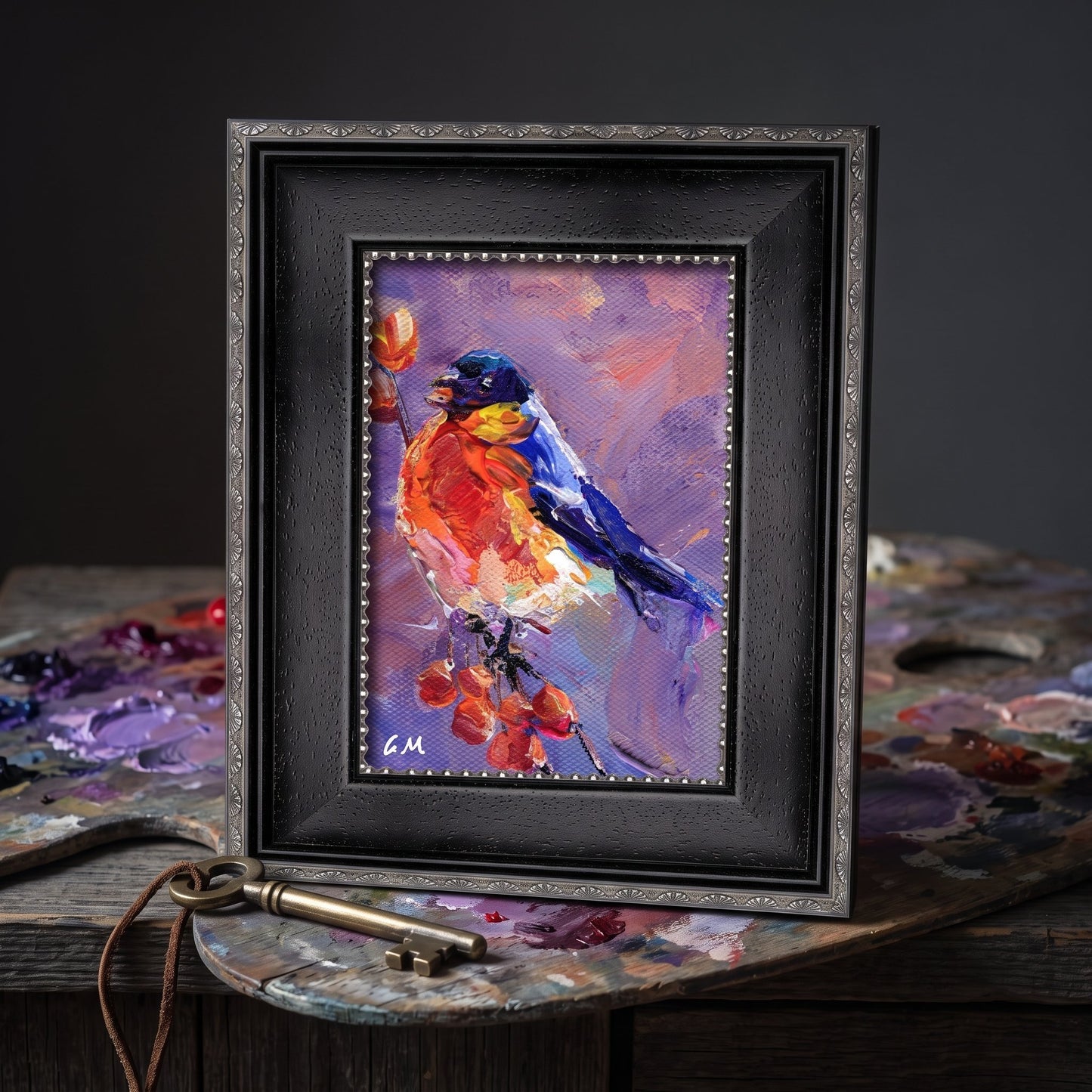 A vividly painted bird perched on berries in a black frame rests on a paint-stained artist's table, surrounded by tools of creation.