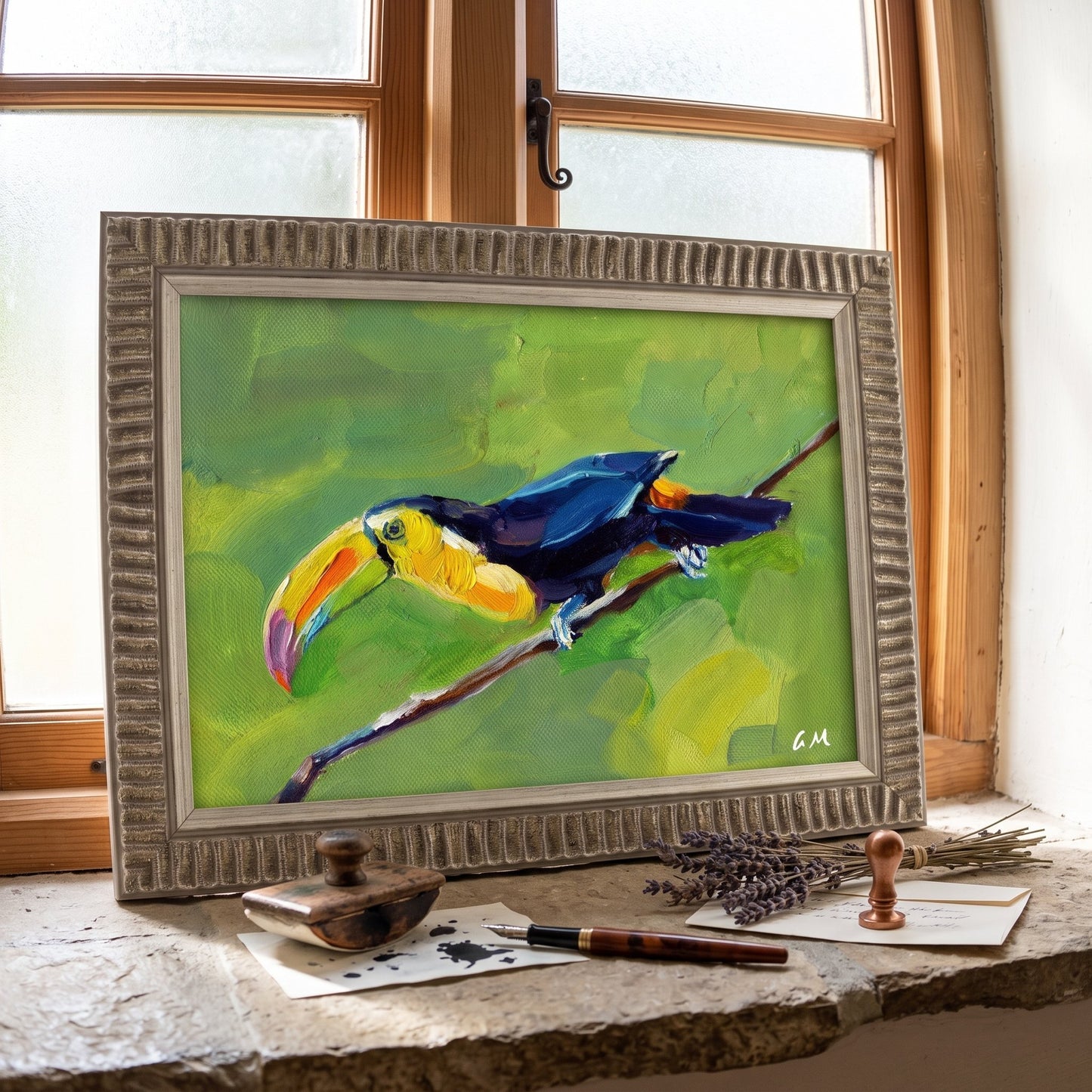 A colorful toucan painting in a textured frame rests on a stone windowsill beside vintage writing tools, bathed in soft daylight.