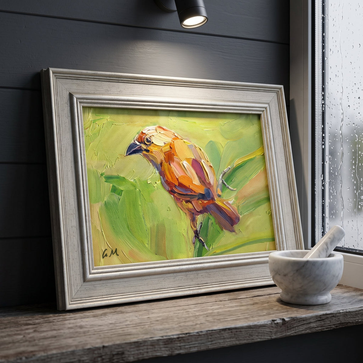 A vividly painted orange bird perched on green foliage rests on a rustic windowsill beneath a spotlight, framed in silver against dark wood paneling.