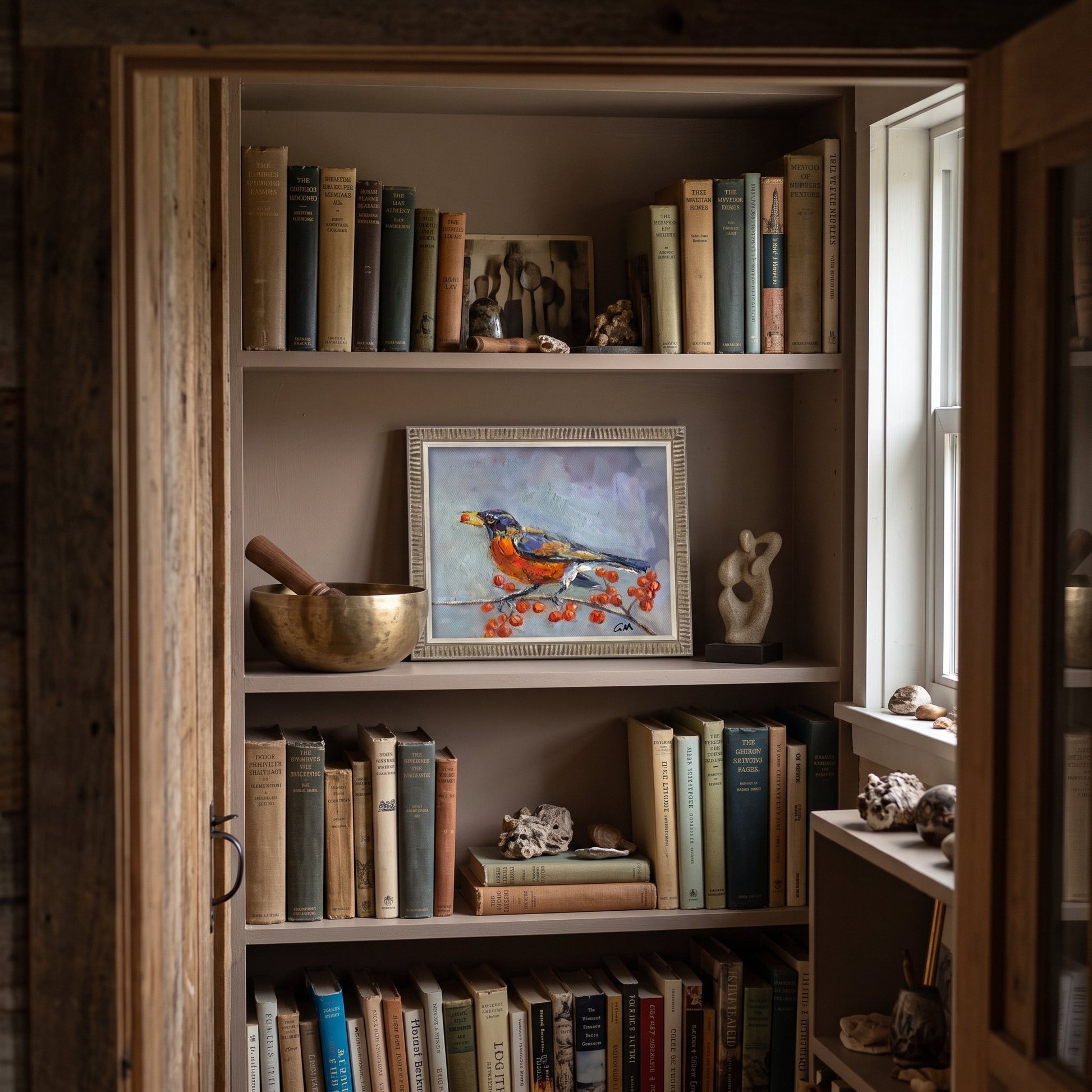 Rustic farmhouse study — original Impressionist bird painting adds vibrant nature-inspired focus to book-lined shelves
