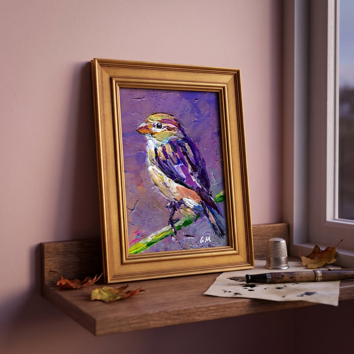 A colorful bird painting in gold frame perched on a wooden windowsill beside scattered autumn leaves and a vintage pen.