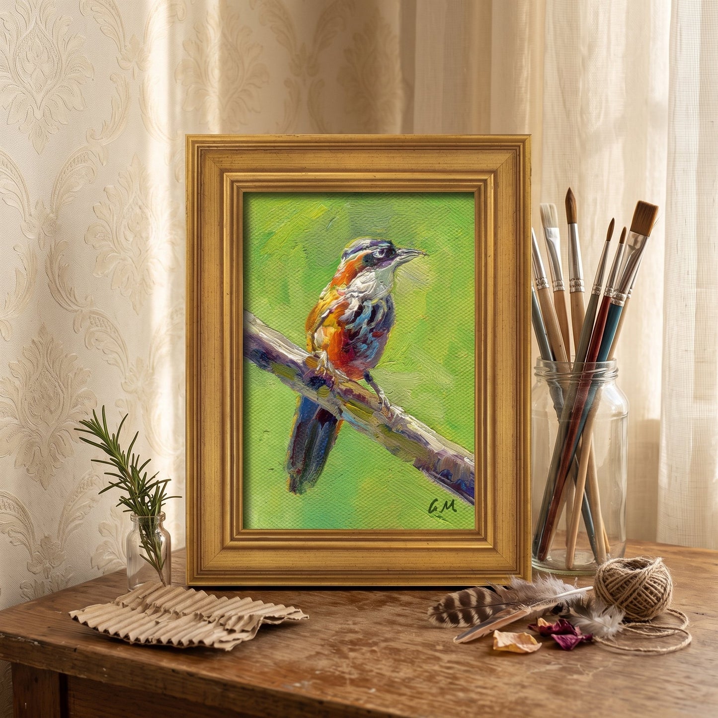 A vividly painted bird perched on a branch in a golden frame sits on a rustic wooden desk beside art supplies, bathed in soft daylight.
