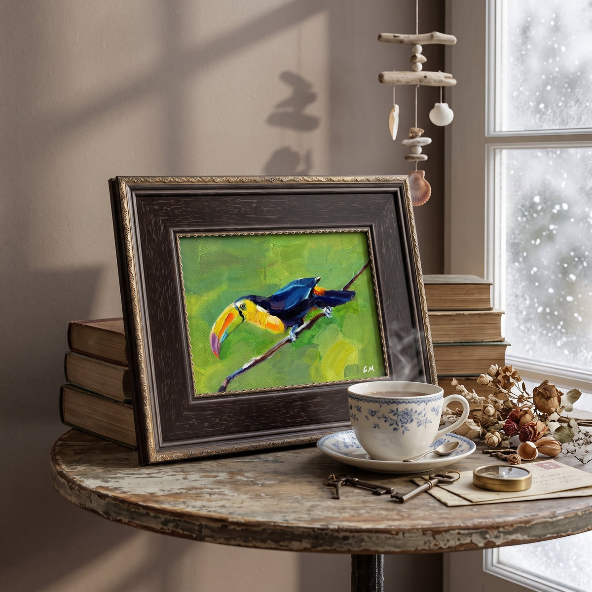 A colorful toucan painting in a dark wood frame sits on a rustic table beside a steaming teacup, bathed in soft daylight from a nearby window.