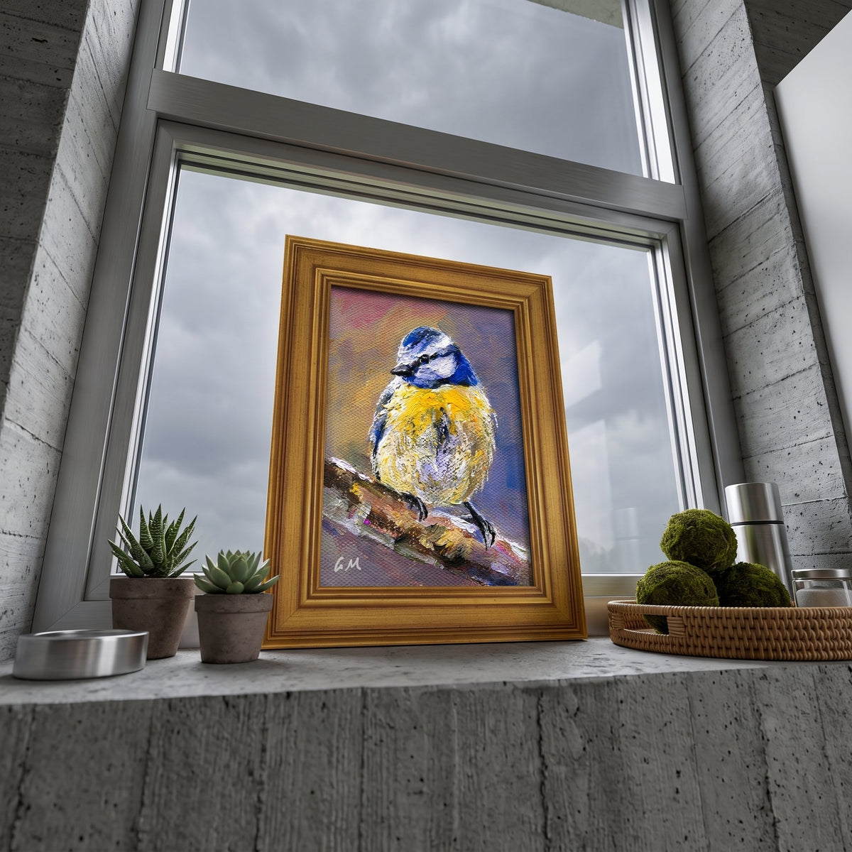 A golden-framed oil painting of a blue and yellow bird perched on a branch sits on a concrete windowsill beside potted succulents, illuminated by soft natural light.