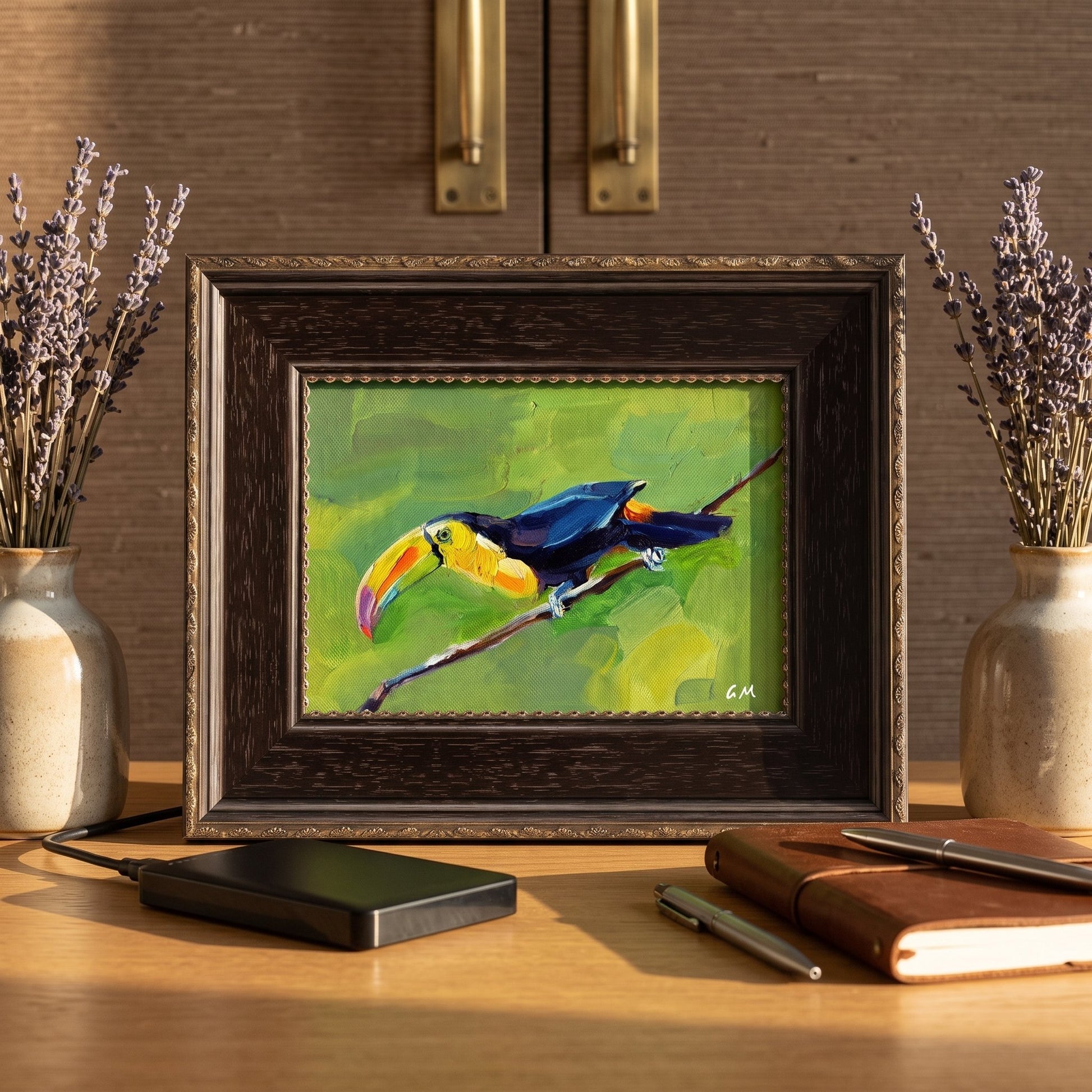 A colorful toucan painting on canvas sits framed on a wooden desk between two lavender vases, illuminated by warm natural light.