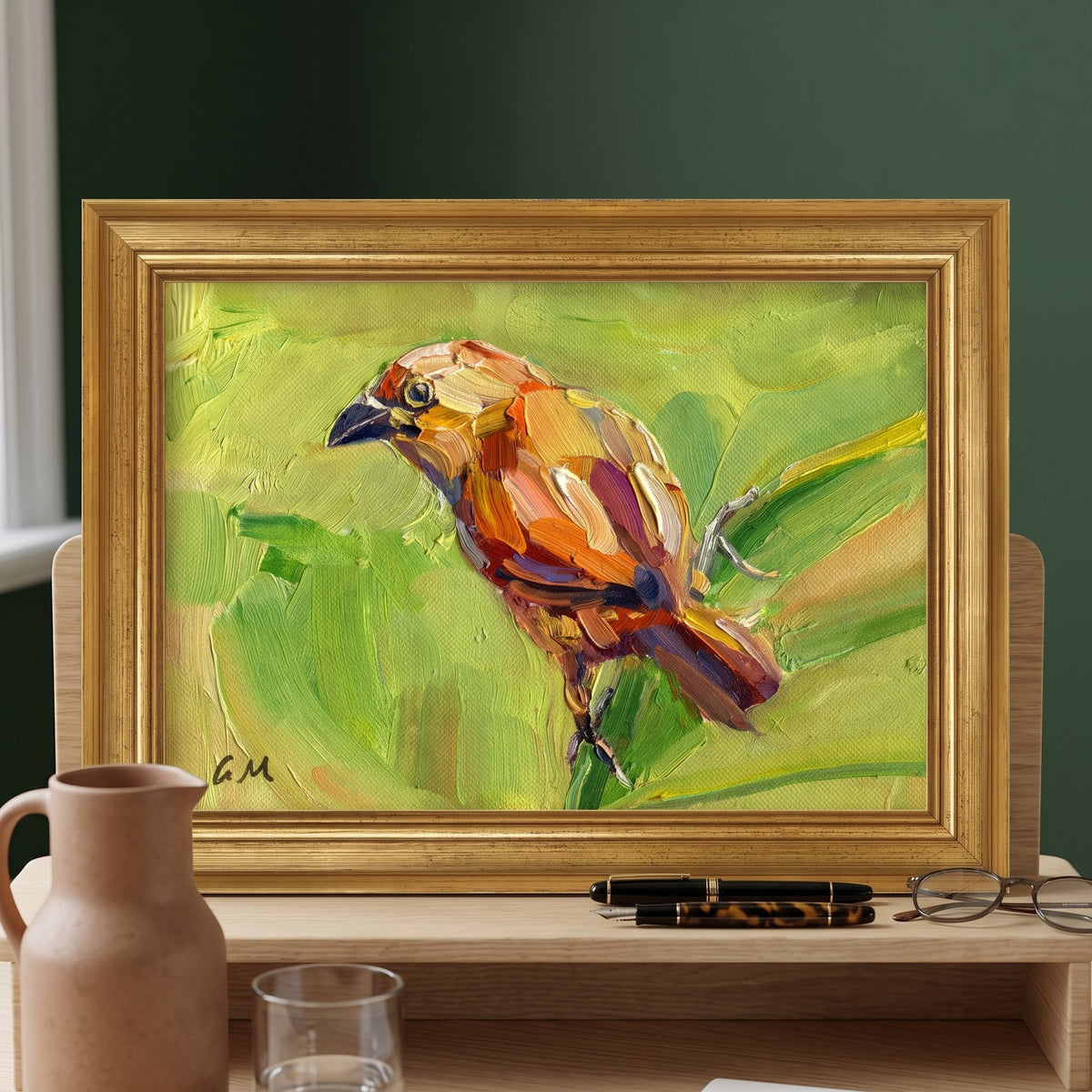 A vividly painted bird in warm hues perches on a leafy branch within a golden frame, resting on a wooden desk beside a terracotta pitcher and reading glasses.