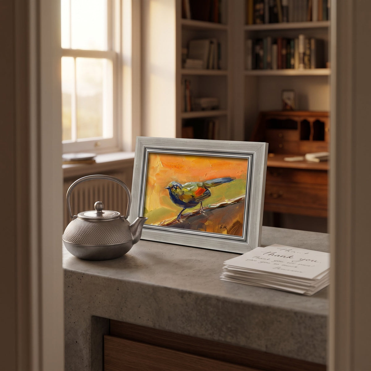 A vividly painted bird in orange, green, and blue perches on a branch in an unframed canvas, resting on a stone counter beside a silver teapot in a sunlit study.