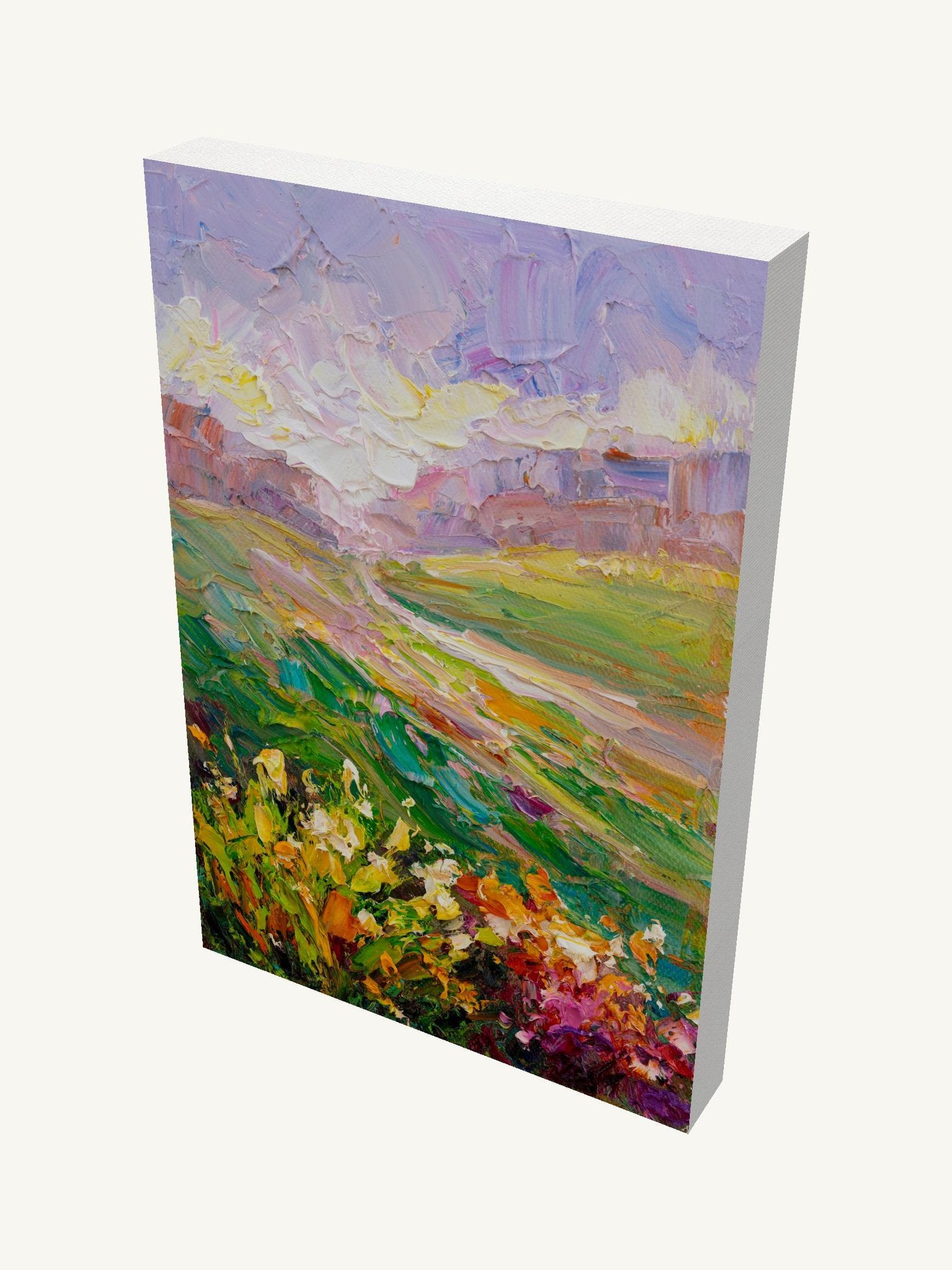 Vertical oil painting on gallery-wrapped canvas depicting a vibrant meadow landscape with floral foreground, rolling hills, and soft sky; viewed at an angle showing depth and side edges